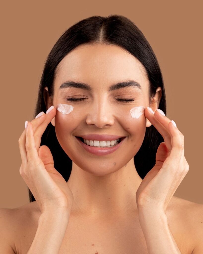 Woman applying top rated eye cream from TikTok under her eyes with a smile on her face
