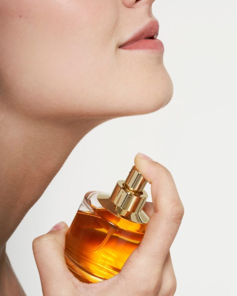 Woman applying everyday perfume to neck using a golden spray bottle