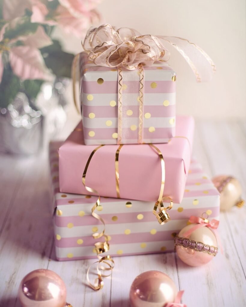 Stack of pink and gold wrapped gift boxes with ribbon bows, perfect for bridesmaid proposal boxes or elegant holiday gifting.