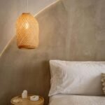 Warm neutral bedroom featuring a cozy bed, woven pendant light, and nightstand decor — a perfect example of cozy bedroom essentials in a minimalist style.