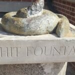 Close-up of Shit Fountain Chicago bronze dog-poop sculpture on a limestone pedestal