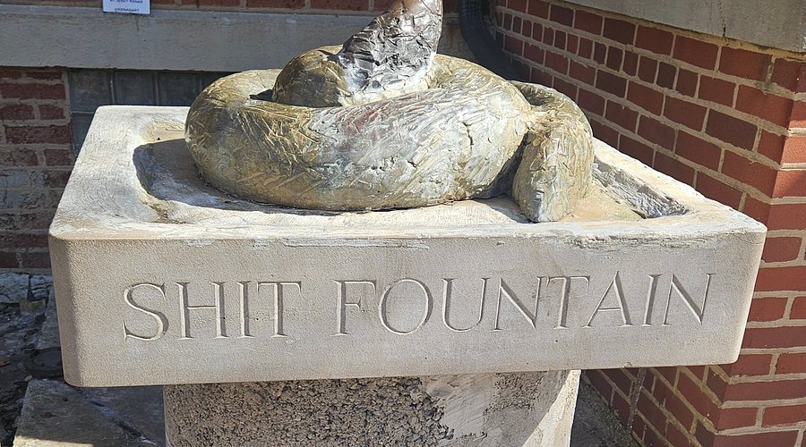Close-up of Shit Fountain Chicago bronze dog-poop sculpture on a limestone pedestal