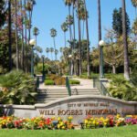 Will Rogers Beverly Hills park entrance sign framed by palms and flower beds