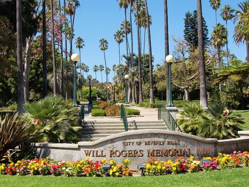 Will Rogers Beverly Hills park entrance sign framed by palms and flower beds