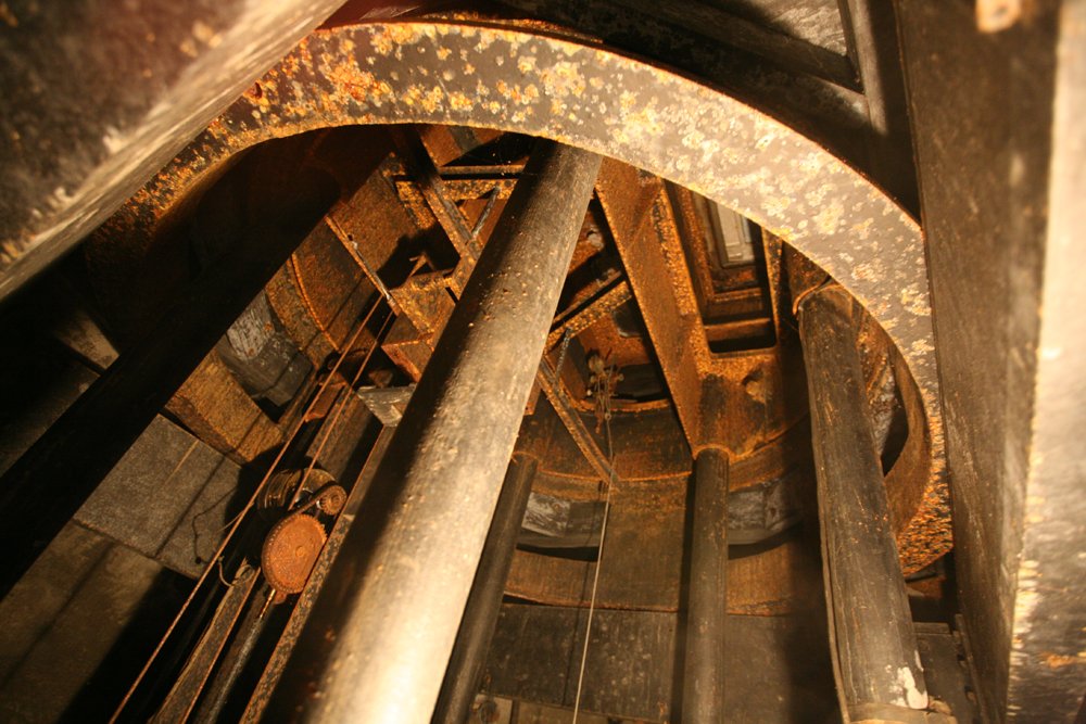 Rust-flecked gear mechanism and support columns inside the rotating dome of Hale Solar Laboratory.