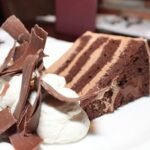 Four-layer chocolate cake with mocha frosting, whipped cream, and chocolate curls served at Tampa’s Harry Waugh Dessert Room