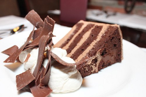 Four-layer chocolate cake with mocha frosting, whipped cream, and chocolate curls served at Tampa’s Harry Waugh Dessert Room