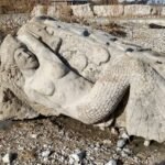 Close-up of the Secret Mermaid Chicago limestone sculpture at Oakwood Beach, showing her scales, tail fin, and serene face