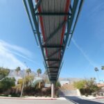 Underside view of Baxandall Bridge Palm Springs pedestrian walkway against blue sky.