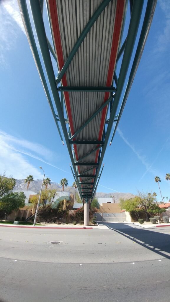 Underside view of Baxandall Bridge Palm Springs pedestrian walkway against blue sky.
