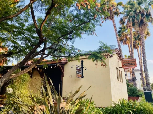 Exterior view of The Luggage Room Pasadena surrounded by palm trees and greenery