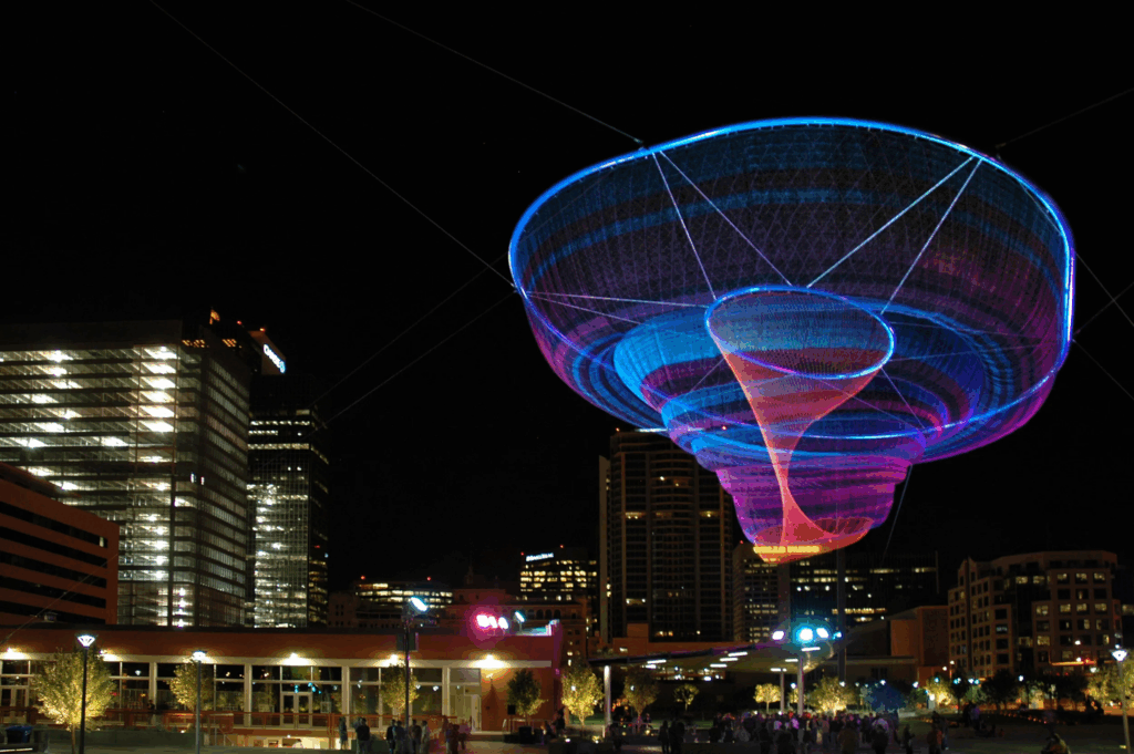 Her Secret Is Patience Phoenix sky sculpture above Civic Space Park with people gathered in the evening