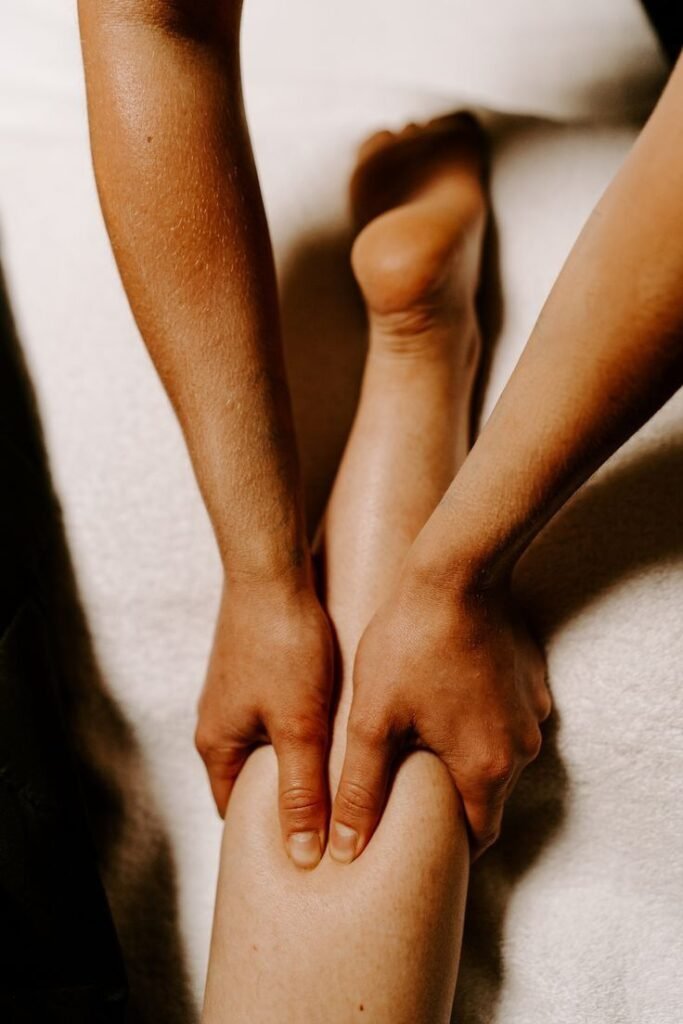 Professional massage therapist applying pressure to relax calf muscles.