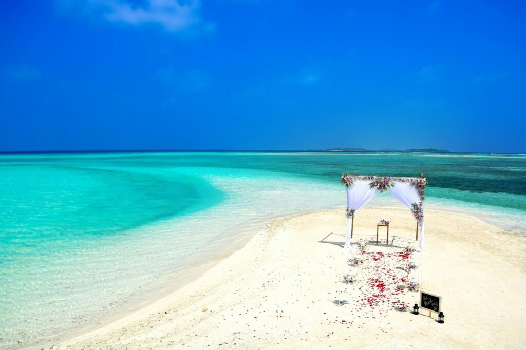 Destination wedding in the U.S. with a romantic beach ceremony setup on white sand by turquoise waters.