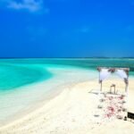 Destination wedding in the U.S. with a romantic beach ceremony setup on white sand by turquoise waters.
