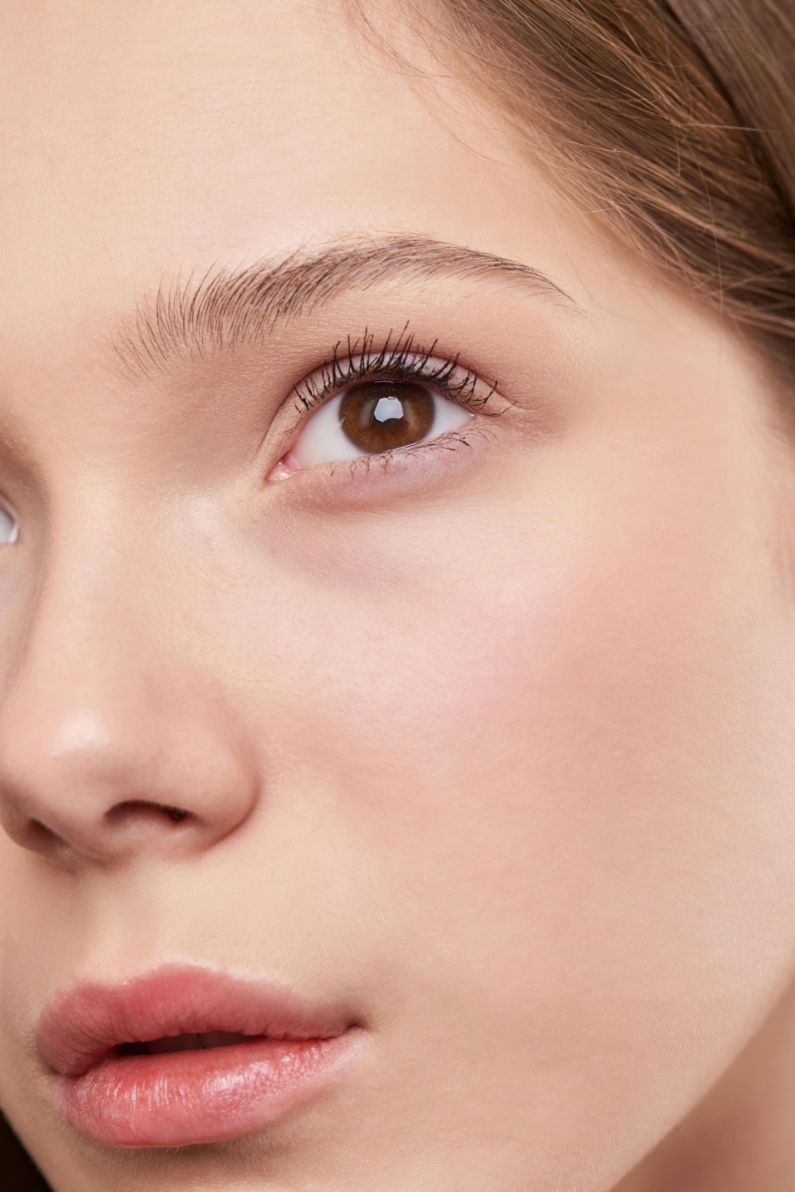 Close-up of a young woman with clear glowing skin and natural makeup.