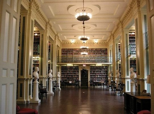 Boston Athenaeum reading room with tall bookshelves, statues, and chandeliers in Boston, Massachusetts.