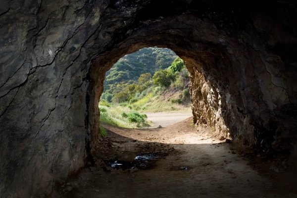 Inside view of Bronson Cave Los Angeles with sunlight and greenery visible at the entrance.
