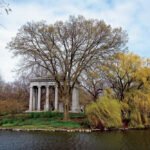 Historic mausoleum surrounded by trees at Graceland Cemetery in Chicago, Illinois, beside a peaceful lake.