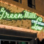 Exterior view of Green Mill Chicago neon sign glowing at night in Uptown.