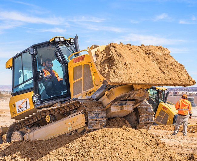 Visitor driving a bulldozer and moving dirt at Dig This Las Vegas experience.