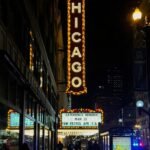 The iconic Chicago Theatre sign illuminated at night with people walking along the street.