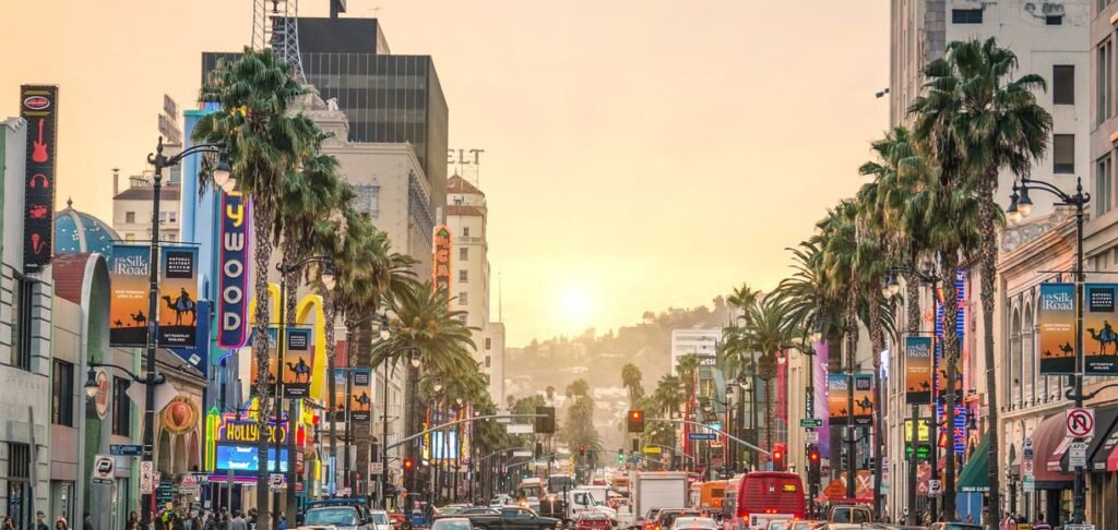 Sunset view of Hollywood Boulevard in Los Angeles with palm trees and traffic — one of the top LA film locations you can visit.