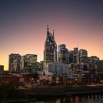 Nashville city skyline at sunset with buildings reflecting on the Cumberland River — a peaceful evening view of Family-Friendly Nashville.
