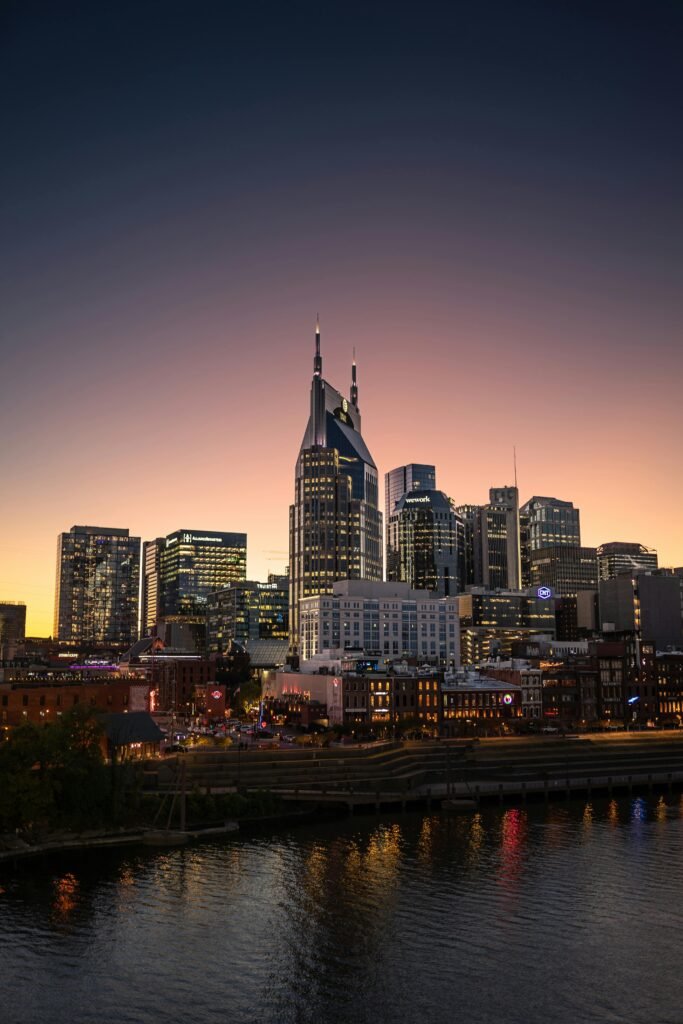 Nashville city skyline at sunset with buildings reflecting on the Cumberland River — a peaceful evening view of Family-Friendly Nashville.