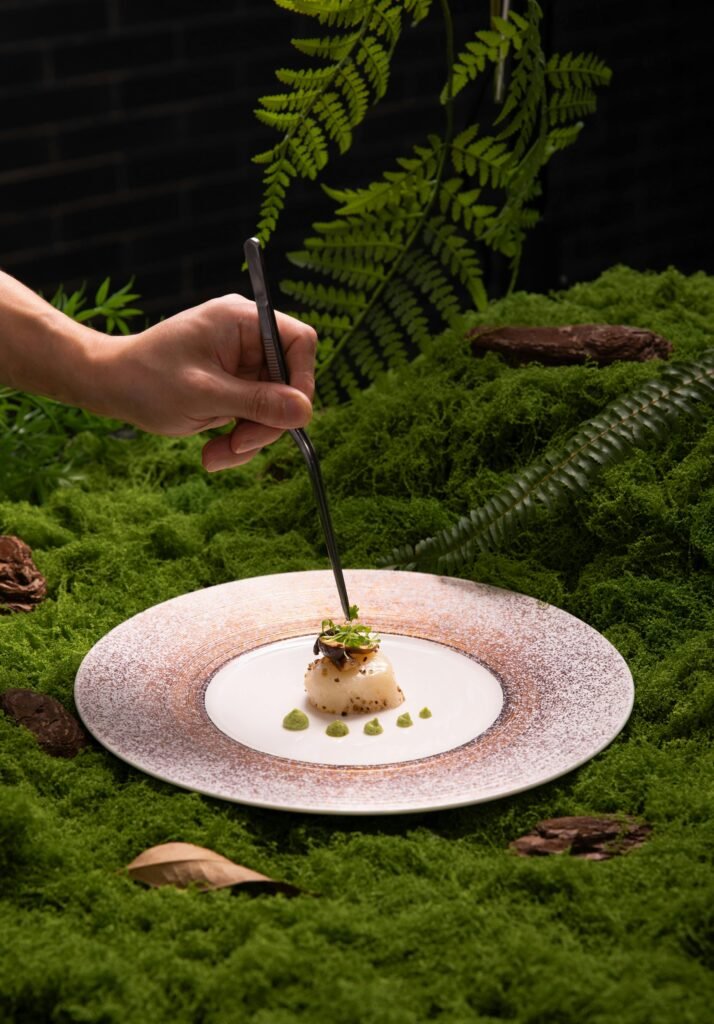 Chef plating gourmet food inspired by Denver breweries and food scene in a nature-style setting.