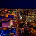 Aerial view of the Las Vegas Strip at night with colorful lights and famous hotels.