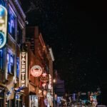 Tourists walking along Broadway in Nashville under glowing neon bar signs