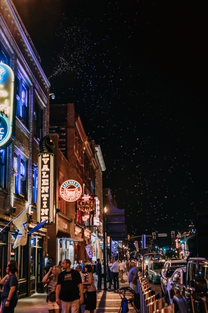 Tourists walking along Broadway in Nashville under glowing neon bar signs