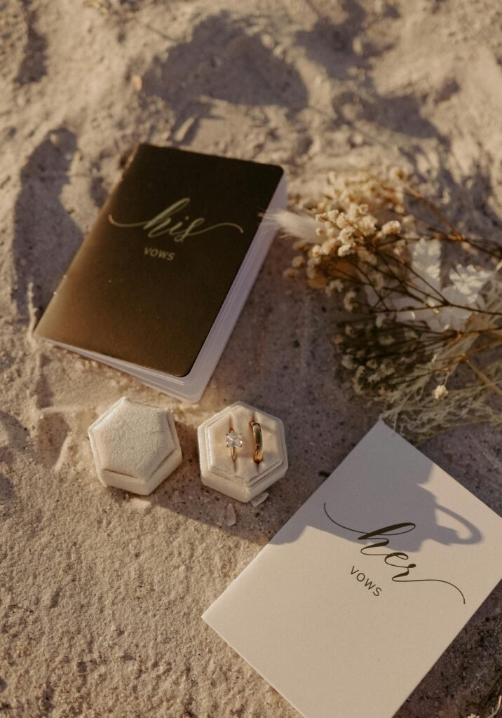 Wedding vow books and gold rings on sandy beach for a destination wedding in Florida on a budget